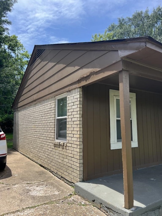View of side of property featuring brick siding and a patio area