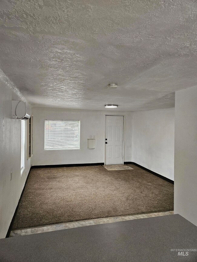 Carpeted spare room with a textured ceiling and a smoke detector