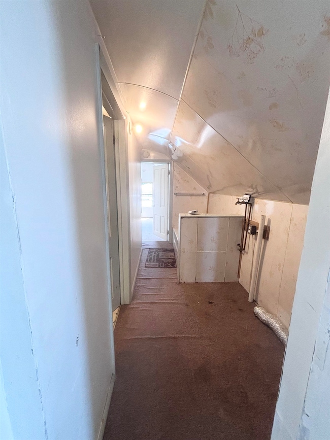 Hallway with vaulted ceiling and carpet floors