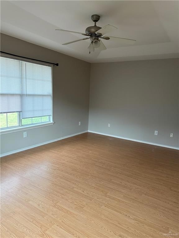 Spare room featuring wood finished floors, ceiling fan, and baseboards
