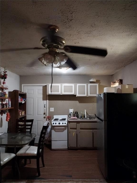Kitchen with freestanding refrigerator, ceiling fan, white electric range, dark wood-style flooring, and a textured ceiling