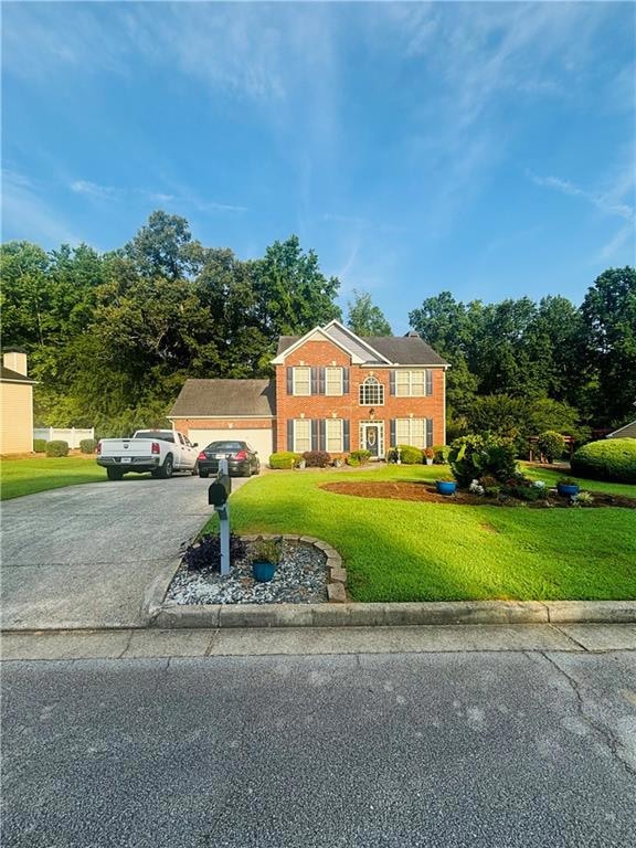 Colonial-style house featuring asphalt driveway, a front yard, an attached garage, and brick siding