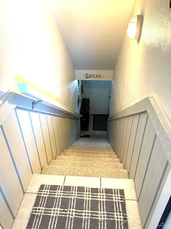 Stairs with a wainscoted wall and a textured wall