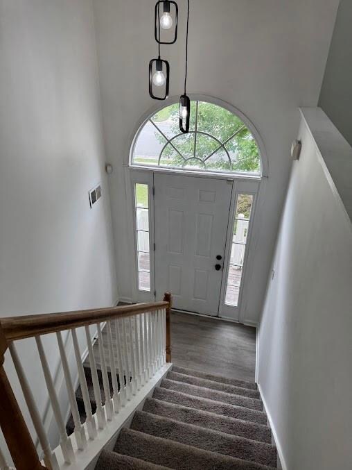 Foyer featuring stairs, a high ceiling, LVP wood-style floors, and baseboards