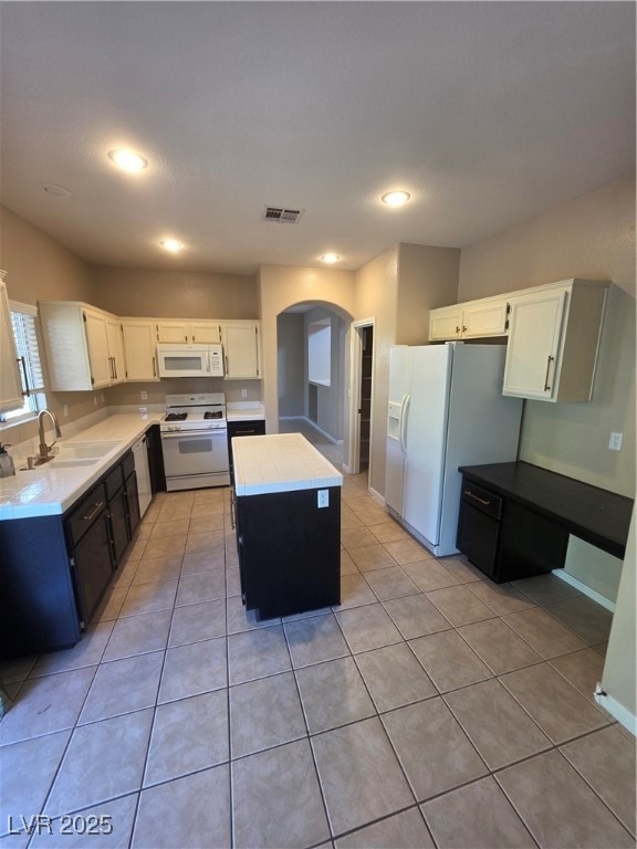 Kitchen featuring white cabinets, a center island, dark cabinetry, stove, and arched walkways