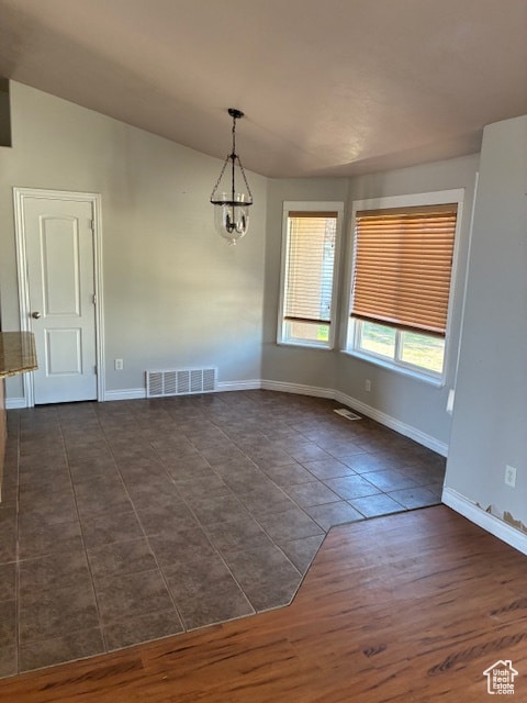Unfurnished dining area featuring a chandelier and dark wood-style floors