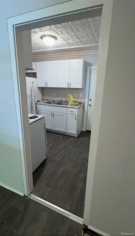 Kitchen featuring light countertops, white cabinetry, dark wood-type flooring, white range, and an ornate ceiling
