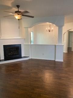 Living room features a fireplace with raised hearth, a chandelier, dark wood-style floors, and arched walkways