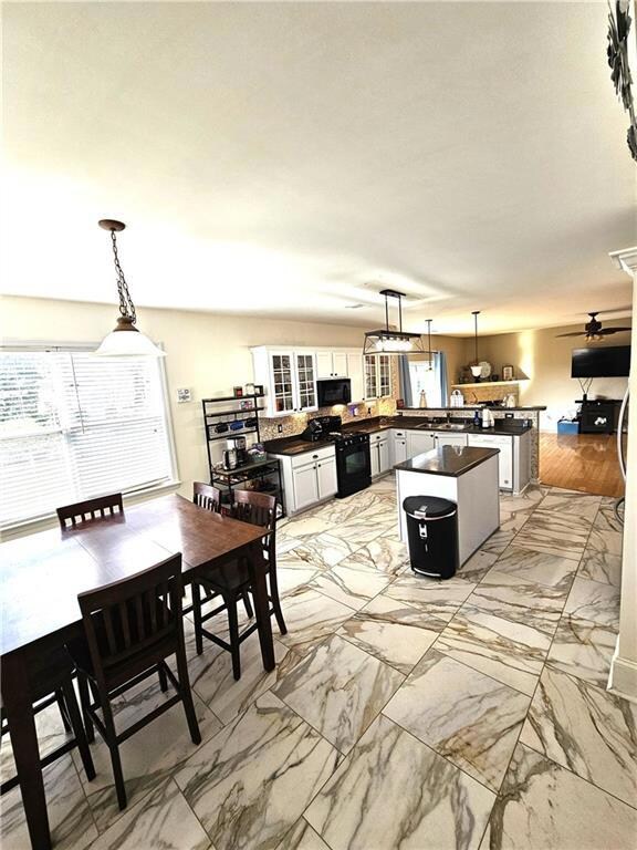 Kitchen with pendant lighting, a peninsula, and light marble finish flooring
