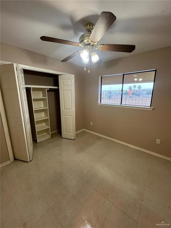 Unfurnished bedroom featuring ceiling fan, light floors, a closet, and baseboards