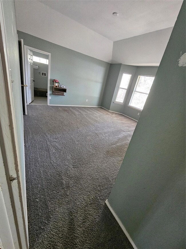 Carpeted empty room with vaulted ceiling