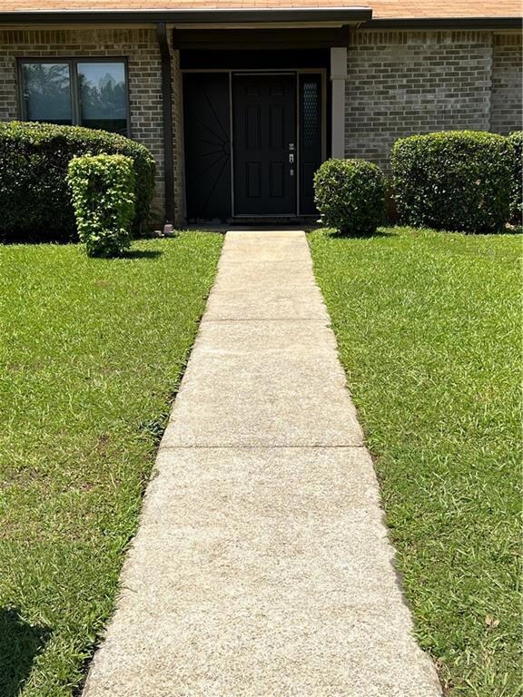 Entrance to property with brick siding and a lawn