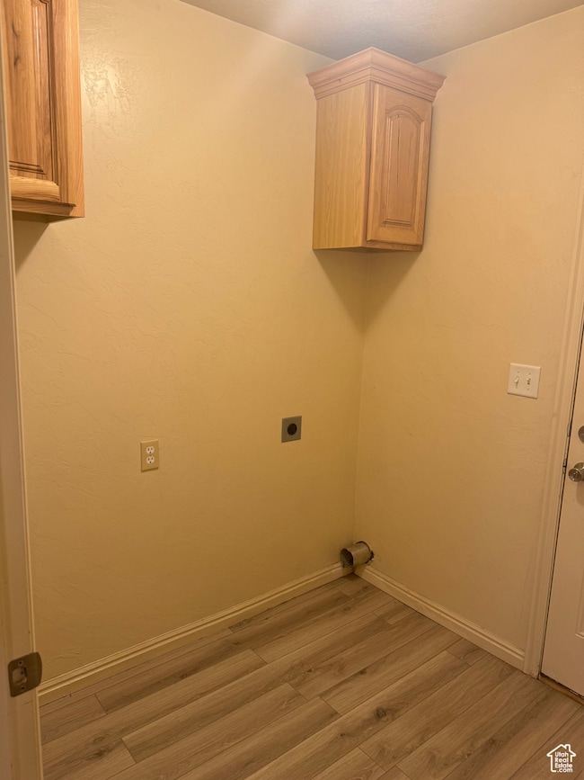 Laundry area featuring cabinets, wood-type flooring, and electric dryer hookup