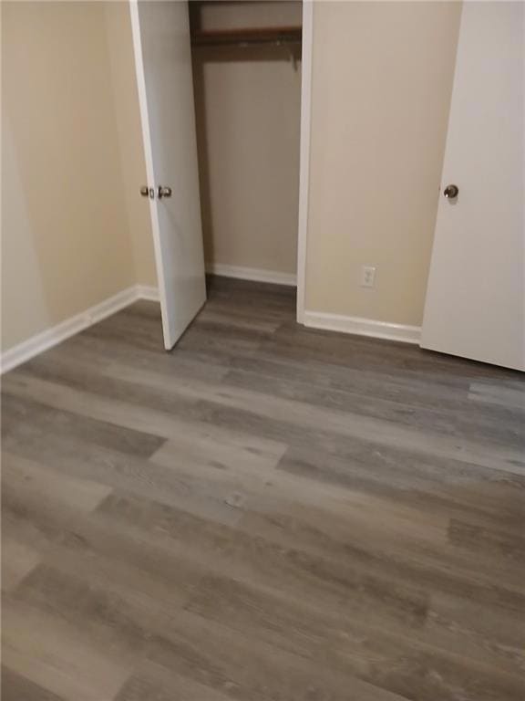 Unfurnished bedroom with a closet and dark hardwoo