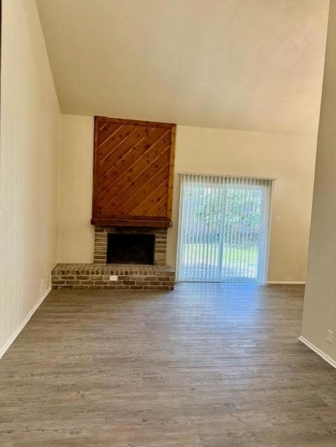 Unfurnished living room featuring a fireplace, light wood-type flooring, and lofted ceiling