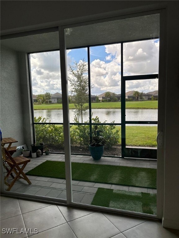 Doorway with a water view, tile patterned floors, and a textured wall