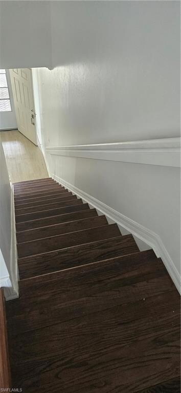 Stairway with wood finished floors and baseboards