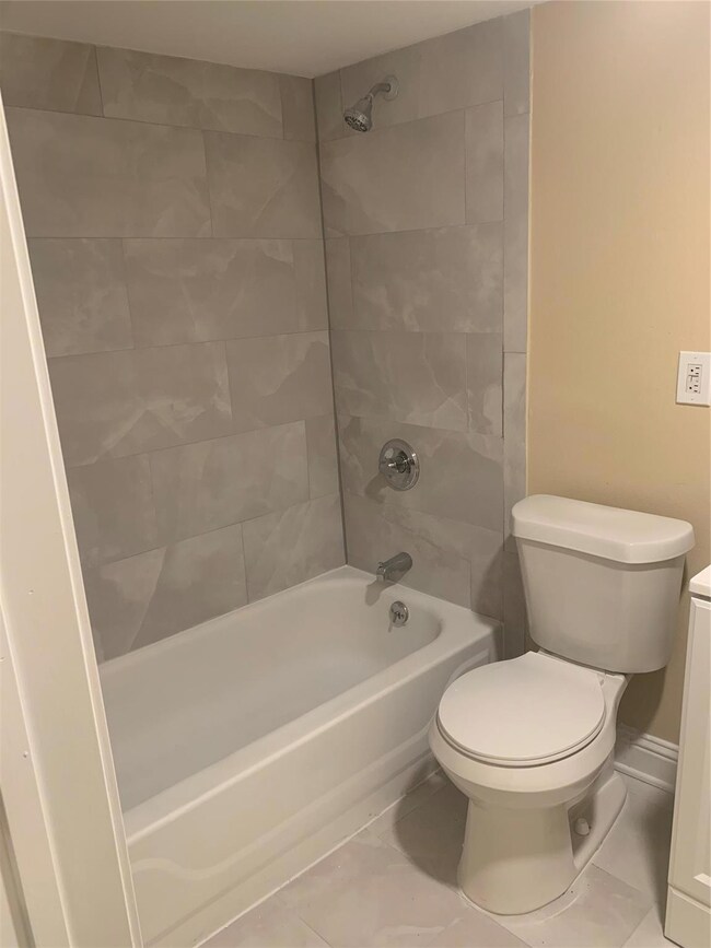 Full bathroom featuring tiled shower / bath, toile