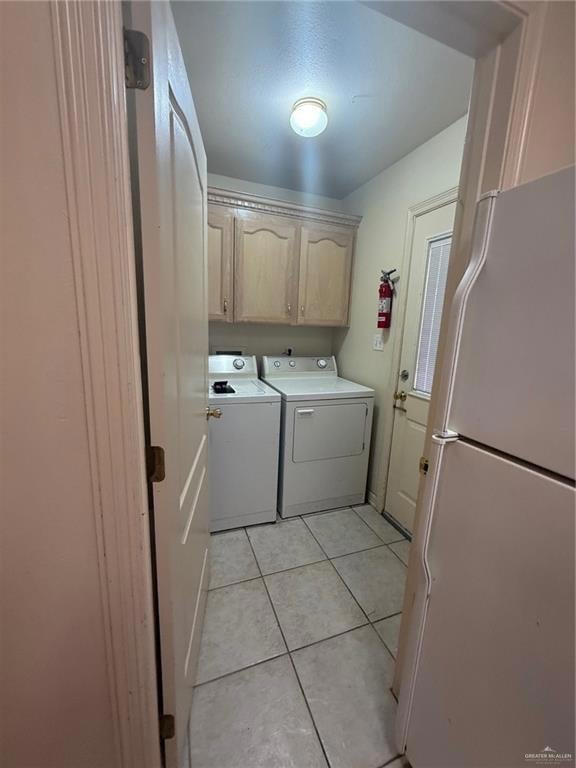 Laundry area featuring independent washer and dryer, cabinet space, and light tile patterned floors