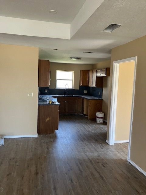 Kitchen with dark countertops, dark wood finished floors, brown cabinets, and a textured ceiling