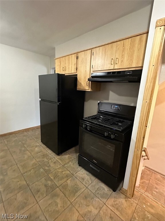 Kitchen with black appliances, light tile floors, and light brown cabinetry