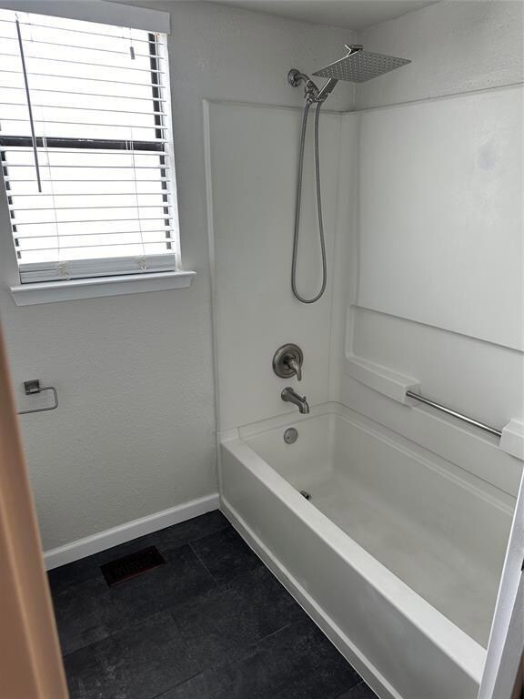 Bathroom with shower / bathtub combination and baseboards