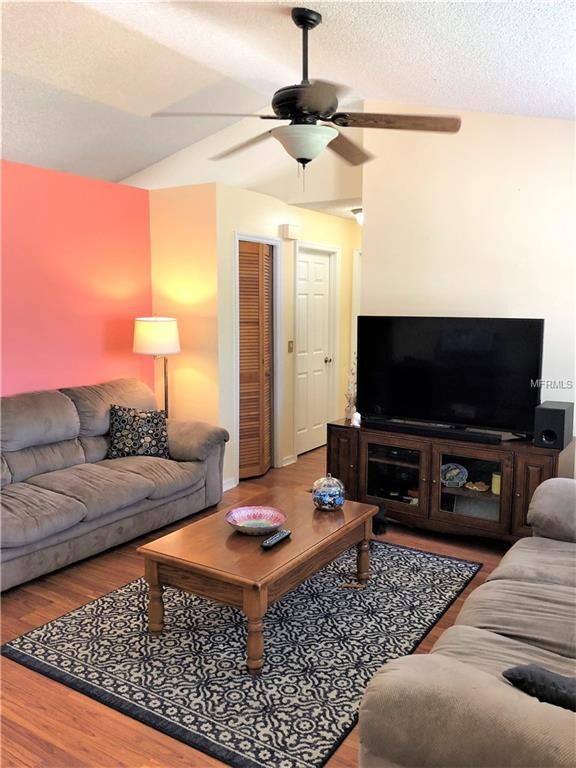 Living room with vaulted ceilings, ceiling fan and