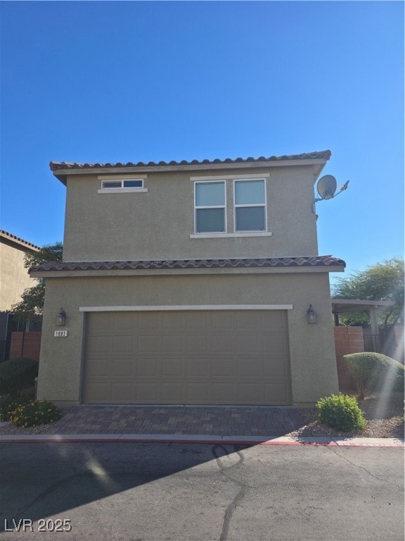 View of front facade with an attached garage, stucco siding, driveway, and a tiled roof