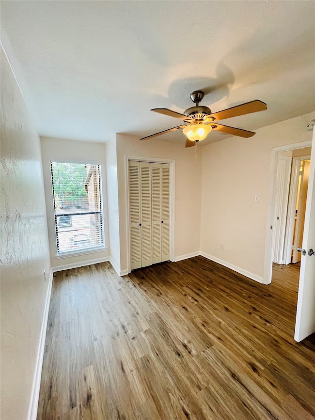 Unfurnished bedroom featuring wood finished floors, ceiling fan, and a closet
