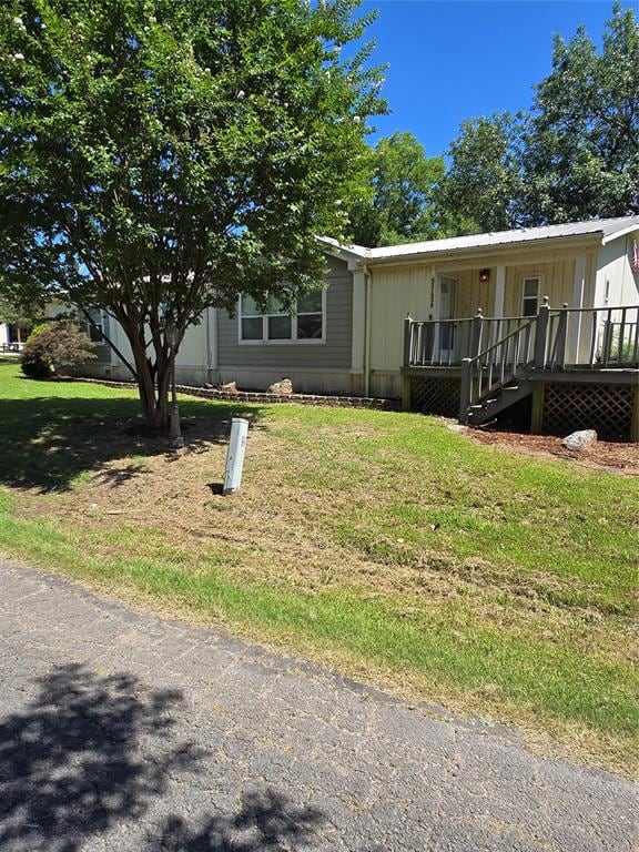 View of front of property featuring a front yard and a wooden deck