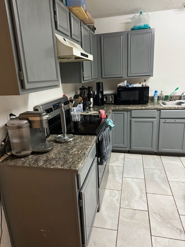 Kitchen featuring gray cabinets, stainless steel electric range, a textured ceiling, under cabinet range hood, and black microwave
