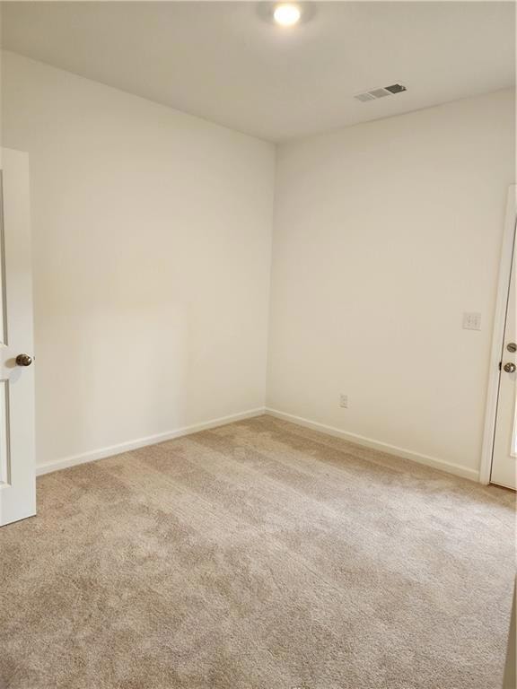 Empty room with carpet floors, visible vents, and 