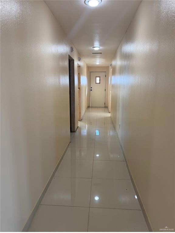 Corridor with light tile patterned flooring and baseboards