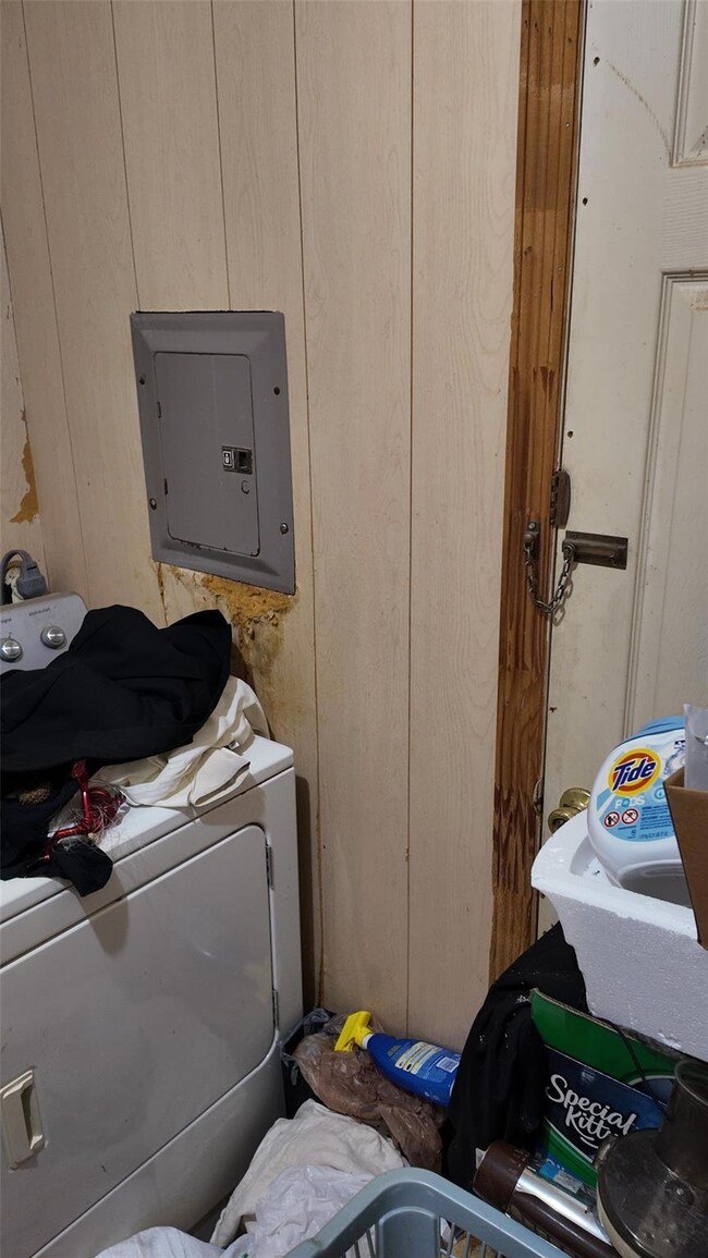 Clothes washing area featuring wood walls, electri