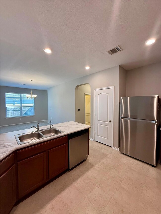 Kitchen featuring light countertops, stainless steel appliances, recessed lighting, arched walkways, and a chandelier