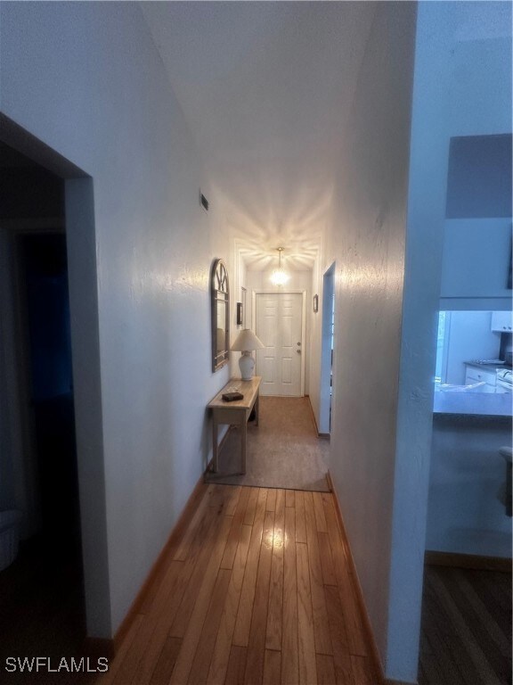 Corridor with wood-type flooring and baseboards