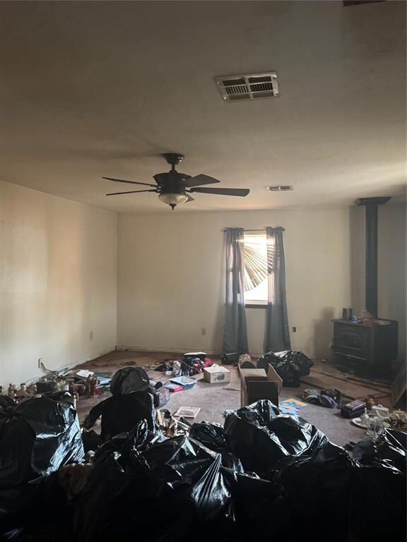 Spare room with a wood stove and ceiling fan