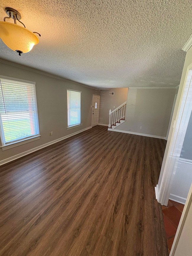 Unfurnished living room with a textured ceiling, dark wood finished floors, and stairway