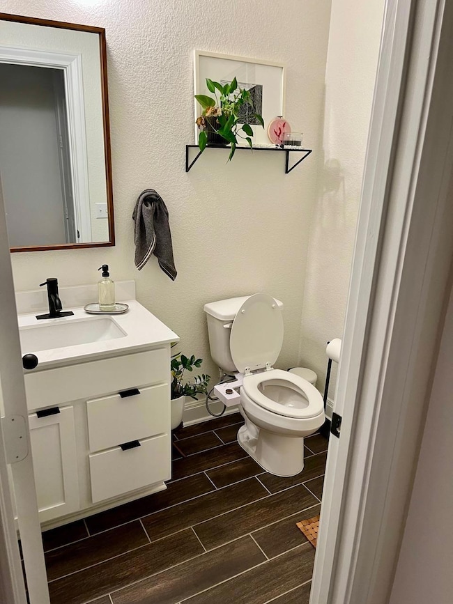 Bathroom featuring wood tiled floors, vanity, toi