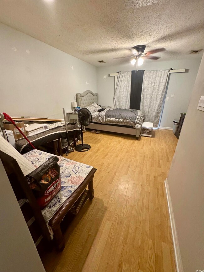 Bedroom with light wood-style floors, a textured ceiling, and ceiling fan