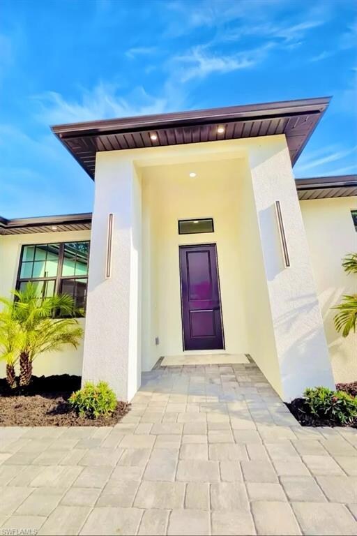Doorway to property featuring stucco siding