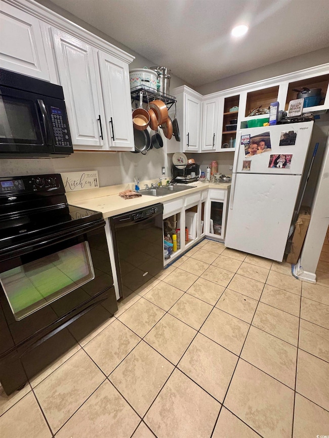 Kitchen with black appliances, white cabinets, light countertops, open shelves, and light tile patterned floors