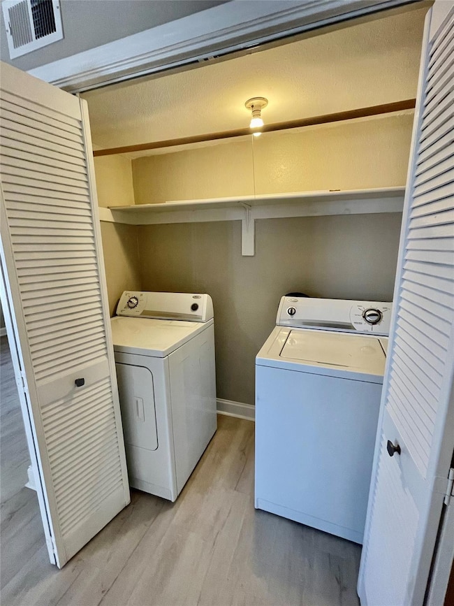Clothes washing area featuring light hardwood / wo