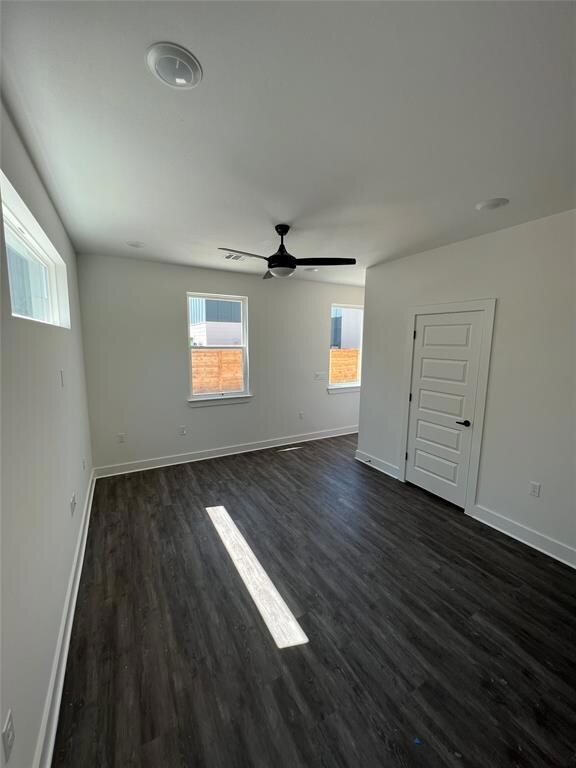 Unfurnished room featuring baseboards, dark wood-