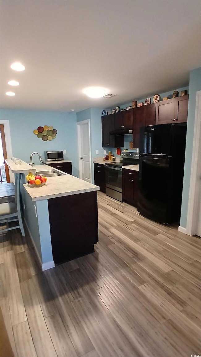 Kitchen with light countertops, appliances with stainless steel finishes, light wood-type flooring, recessed lighting, and under cabinet range hood