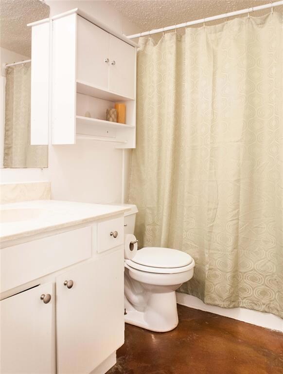 Full bath featuring a textured ceiling, vanity, c