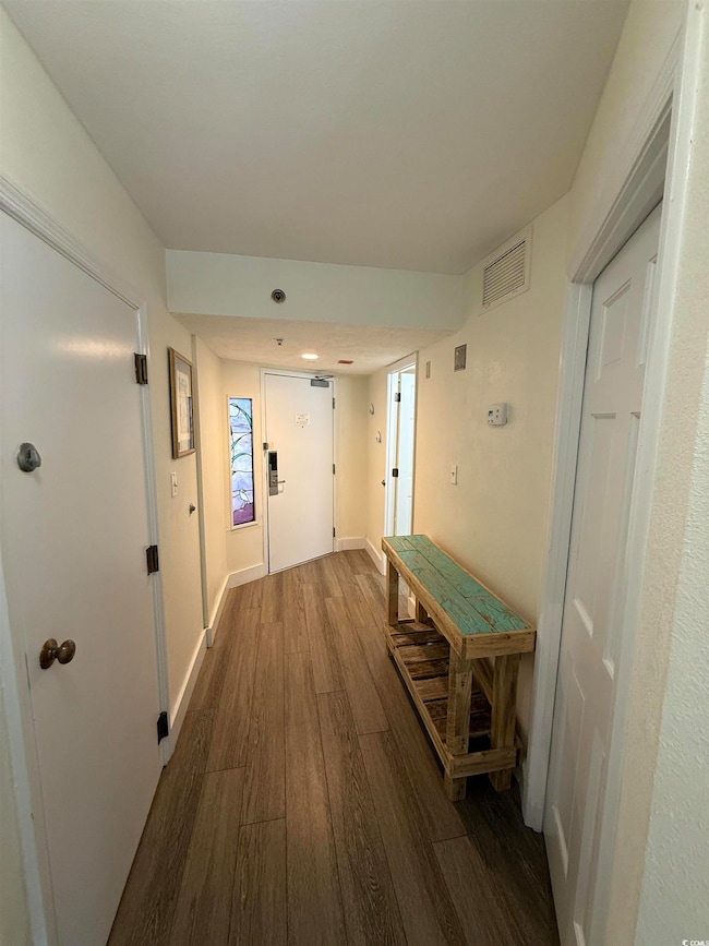 Corridor with dark wood-style flooring and baseboards