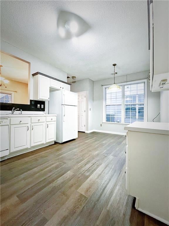 Kitchen with a textured ceiling, white cabinetry, 
