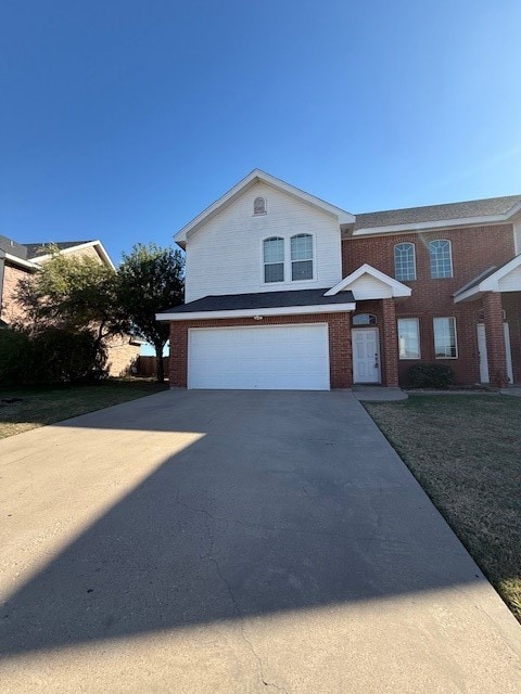 View of front of house featuring driveway, brick siding, and an attached garage