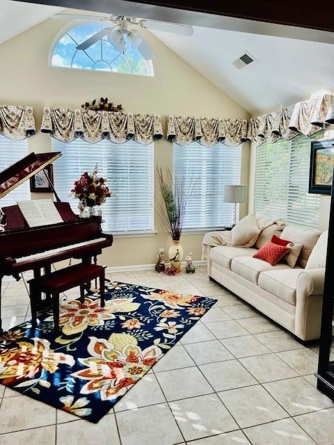 Living room with lofted ceiling, light tile patterned floors, a ceiling fan, and baseboards